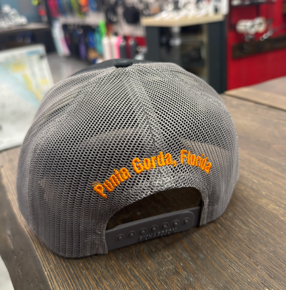 Gray mesh cap with 'Punta Gorda, Florida' text on a wooden surface.