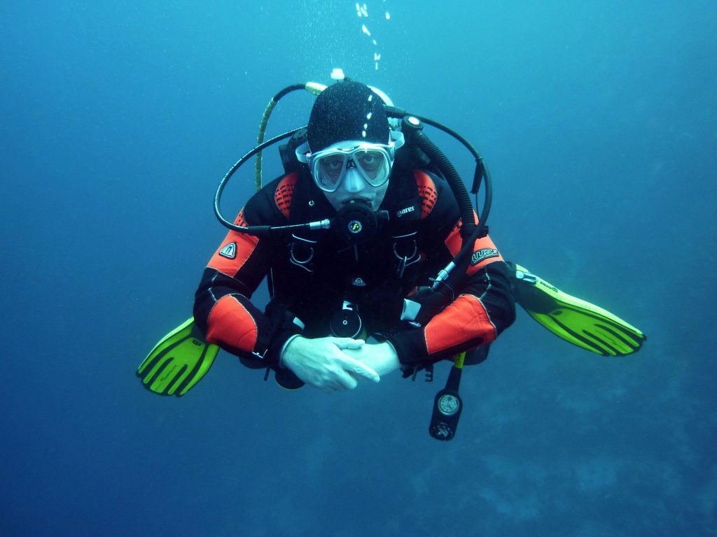 A diver in a drysuit exploring the ocean depths with full scuba gear.