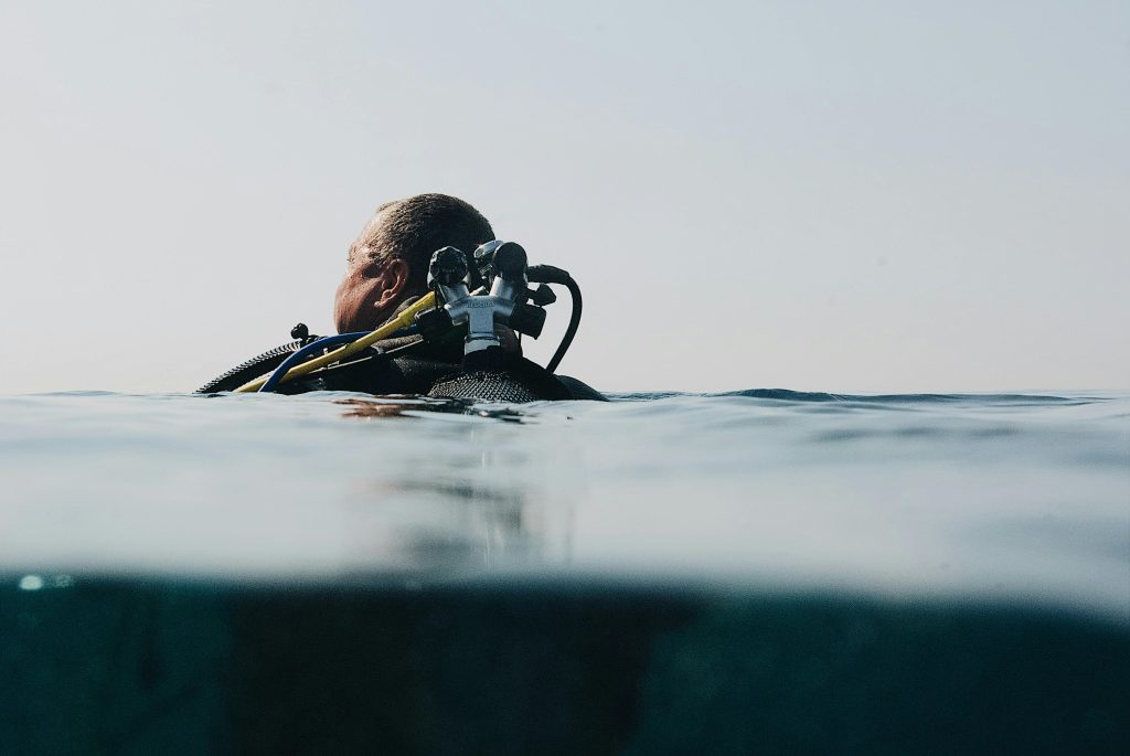 A scuba diver floats at the water's surface in an over-under shot, capturing ocean exploration.